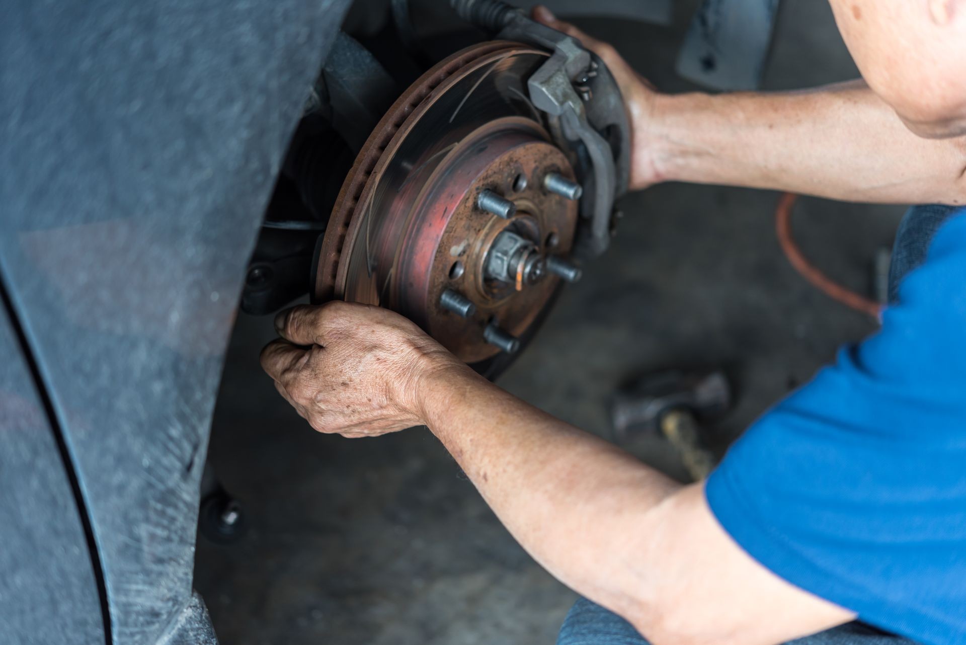 Car mechanic or serviceman checking a disc brake and asbestos brake pads it's a part of car use for stop the car for safety at front wheel this a new spare part for repair at car garage