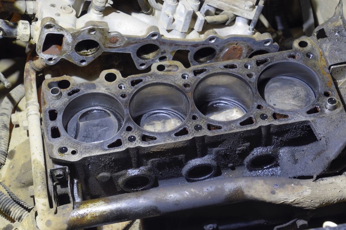 The cylinder block of the four-cylinder engine. Disassembled motor vehicle for repair. Parts in engine oil. Car engine repair in the service.